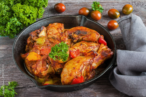 Chakhokhbili, chicken stew, cooked with tomatoes, bell peppers, spices and herbs. Dark wooden background.