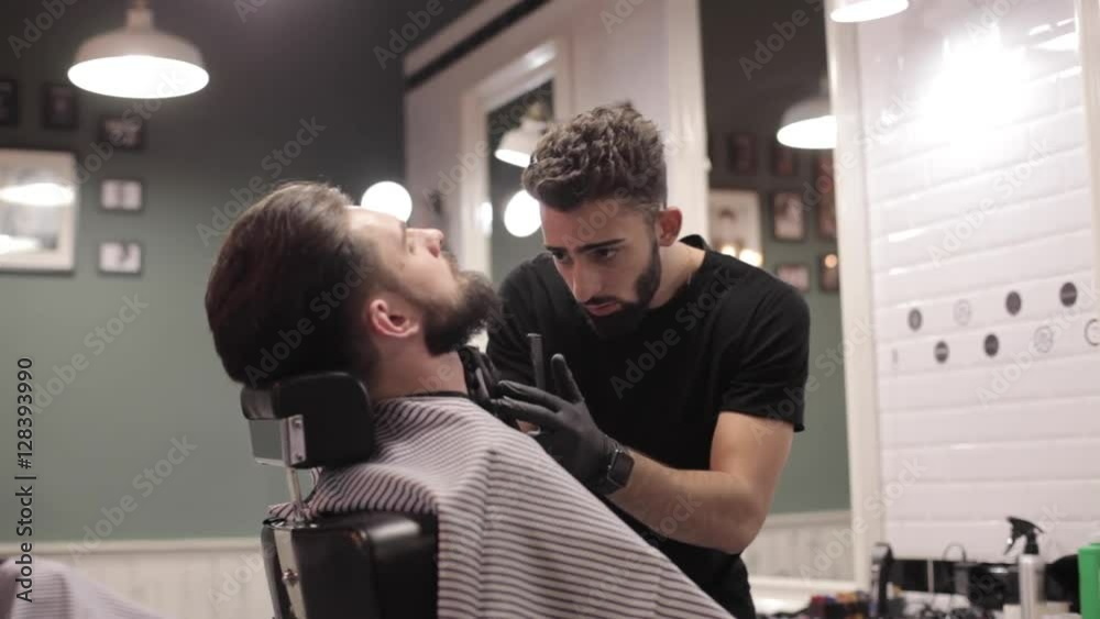 Barber cutting beard with electric razor at a barber shop. Barber cutting beard with electric razor at a barber shop.