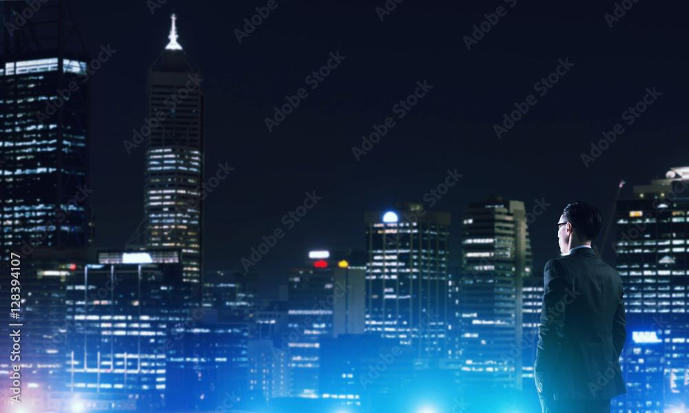 Businessman viewing night glowing city Businessman viewing night glowing city