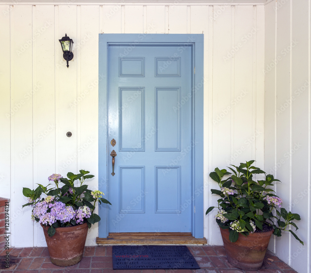 Naklejka premium A front entrance of a home with a blue door, Blue front door with flower pots
