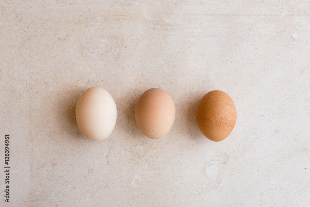 High angle view of white, beige and brown eggs on natural limestone background High angle view of white, beige and brown eggs on natural limestone background