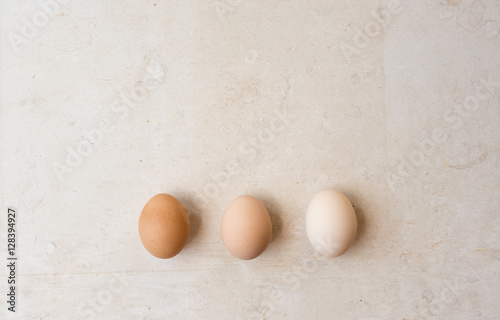 High angle view of white, beige and brown eggs on natural limestone background with copy space at top