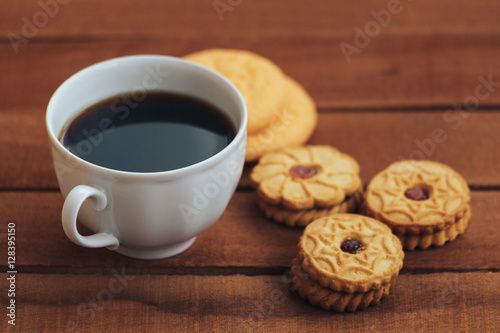 cup of hot coffee and cookies on wooden table background