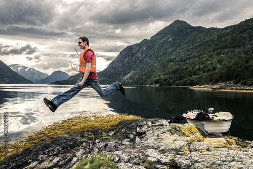 Young man is jumping on stone, Kannesteinen, Norway