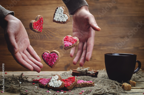 Male hand with flying cookies in the forms of hearts