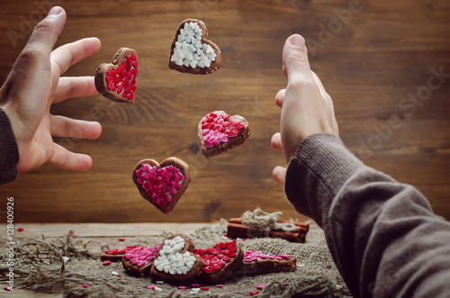Male hand with flying cookies in the forms of heart