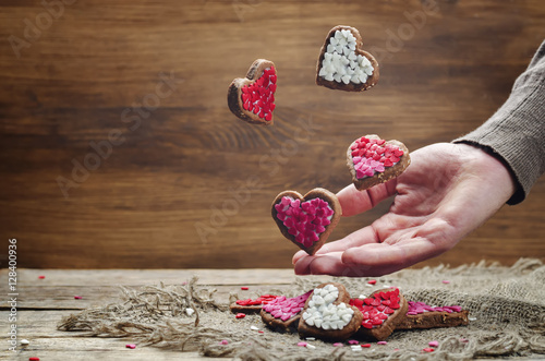 Male hand with flying cookies in the forms of hearts