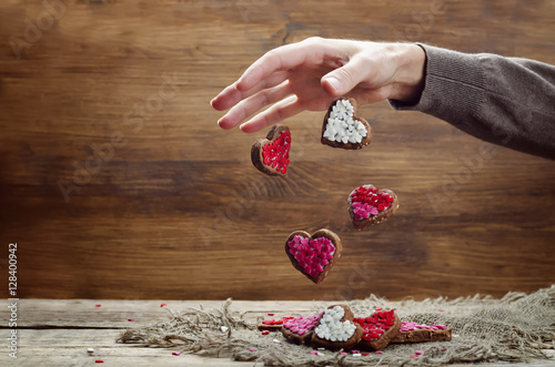 Male hand with flying cookies in the forms of hearts