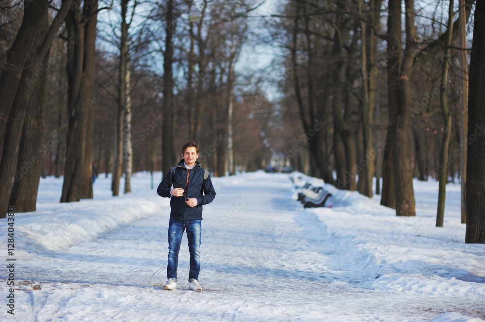 Stylish young man walking through the snow-covered Park on a clear winter day.