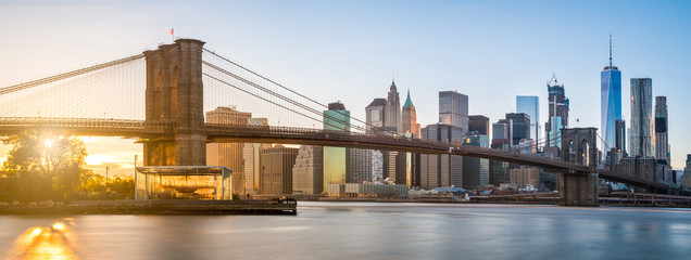 The panorama view of Brooklyn Bridge with Lower Manhattan in the background, lit by sunset