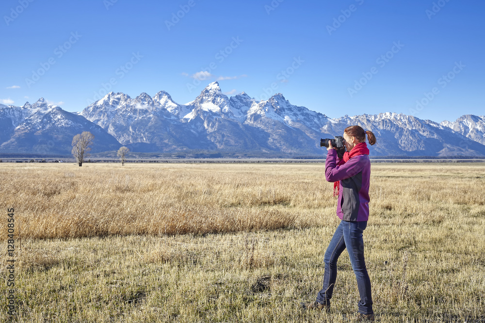 Female fit hiker taking pictures with DSLR camera in the Grand Teton National Park, Wyoming, USA.