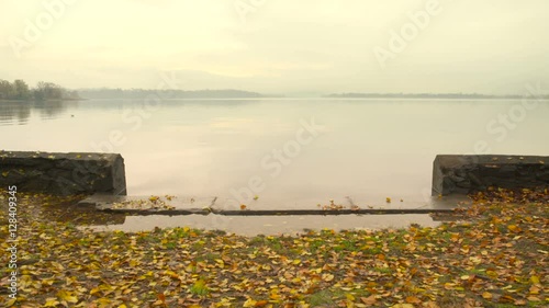 On the shore of a quiet lake with leaves in autumn photo