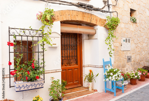 Chair and flower pots decorate home exterior in narrow Spanish street photo