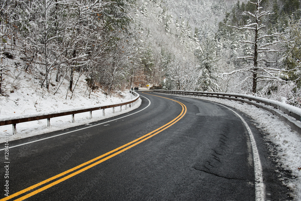 Clean winter road on mountain with turns and curve with trees under the snow. Winter road with yellow marking double line and singns at winter season.