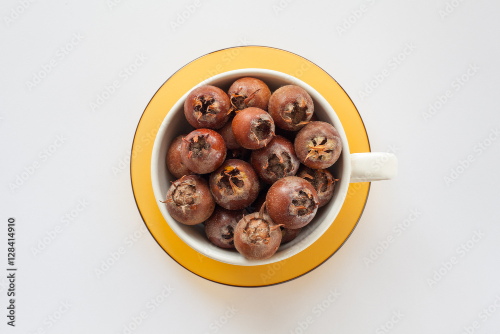 white bowl on a yellow saucer full of sweet medlar on a white background white bowl on a yellow saucer full of sweet medlar on a white background