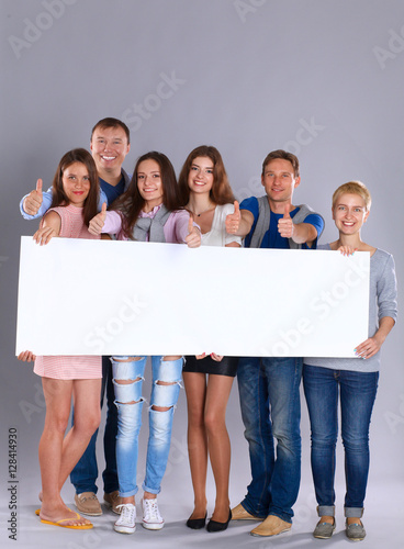 Happy young group of people standing together and holding a blank