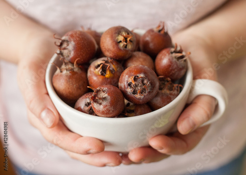 фотографія Women hands holding a white bowl full of medlar