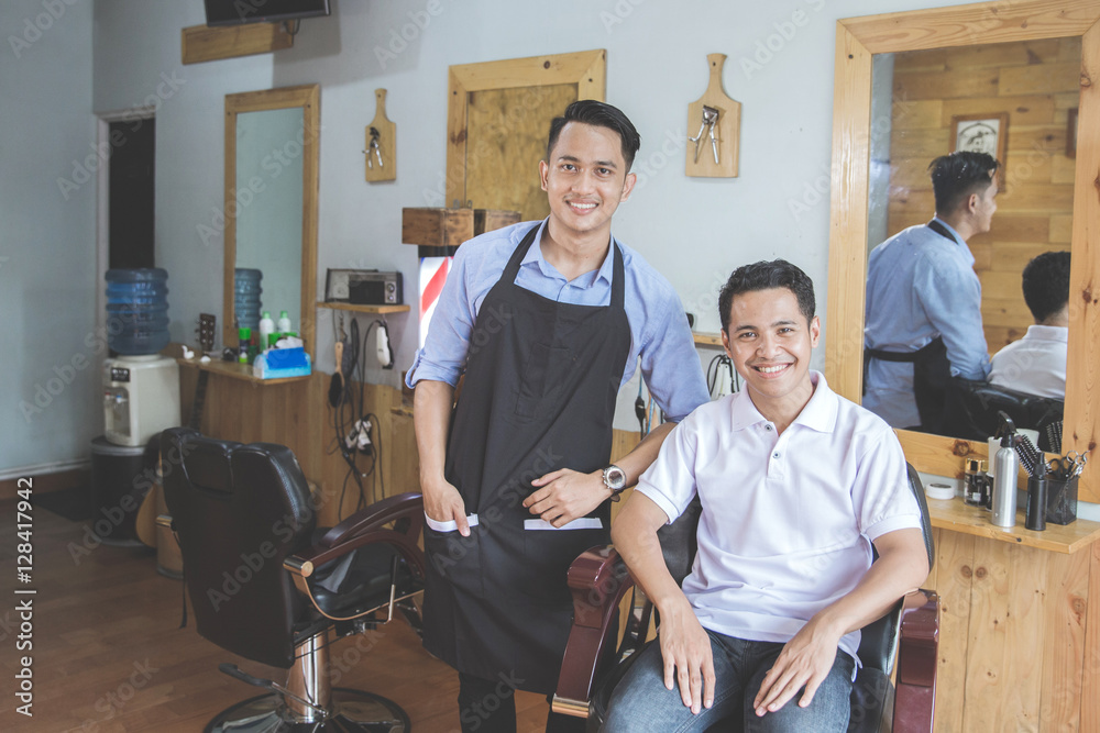 barber and his client smiling to camera in barbershop barber and his client smiling to camera in barbershop