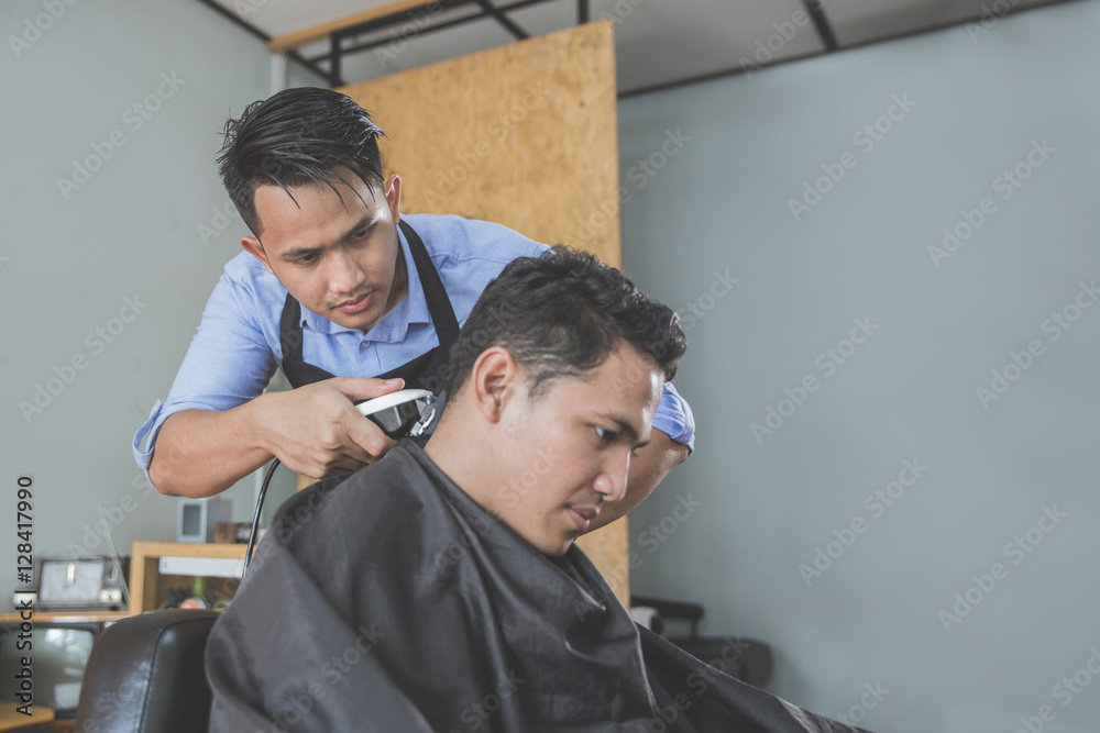 barber making haircut of attractive man in barbershop barber making haircut of attractive man in barbershop