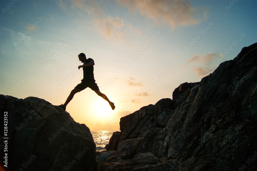 Man jump through the gap between hill.man jumping over cliff on sunset  background,Business concept idea Stock Photo | Adobe Stock
