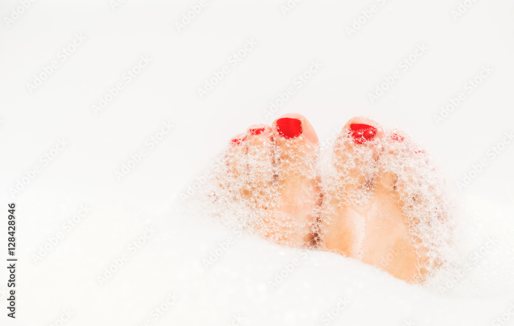 Fototapeta premium Feet with red nails soaking in spa bath