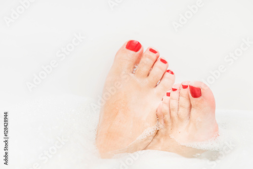 Feet with red nails soaking in spa bath