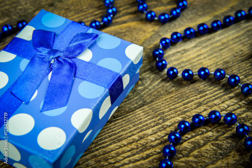 beautiful blue a present with blue beads on a wooden background