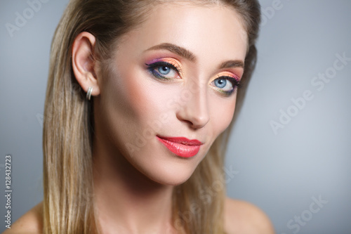 Beauty portrait of a beautiful woman with bright multicolored make-up isolated on a gray background.