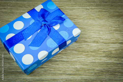 beautiful blue gift with polka dots on a wooden background 
