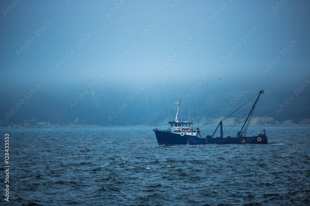 Trawler fishing boat sailing in open waters on a cold and foggy Trawler fishing boat sailing in open waters on a cold and foggy