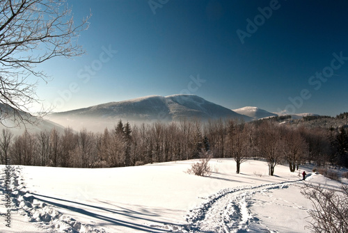winter in Morvskoslezske Beskydy mountains bellow Lysa hora hill with snow, hiking trail, trees, hills and clear sky