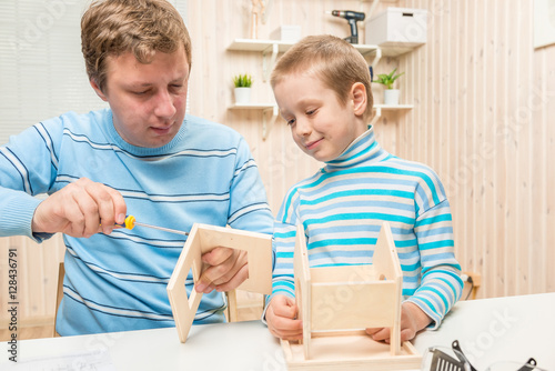 Tableau sur toile father shows his son how to build a bird feeder