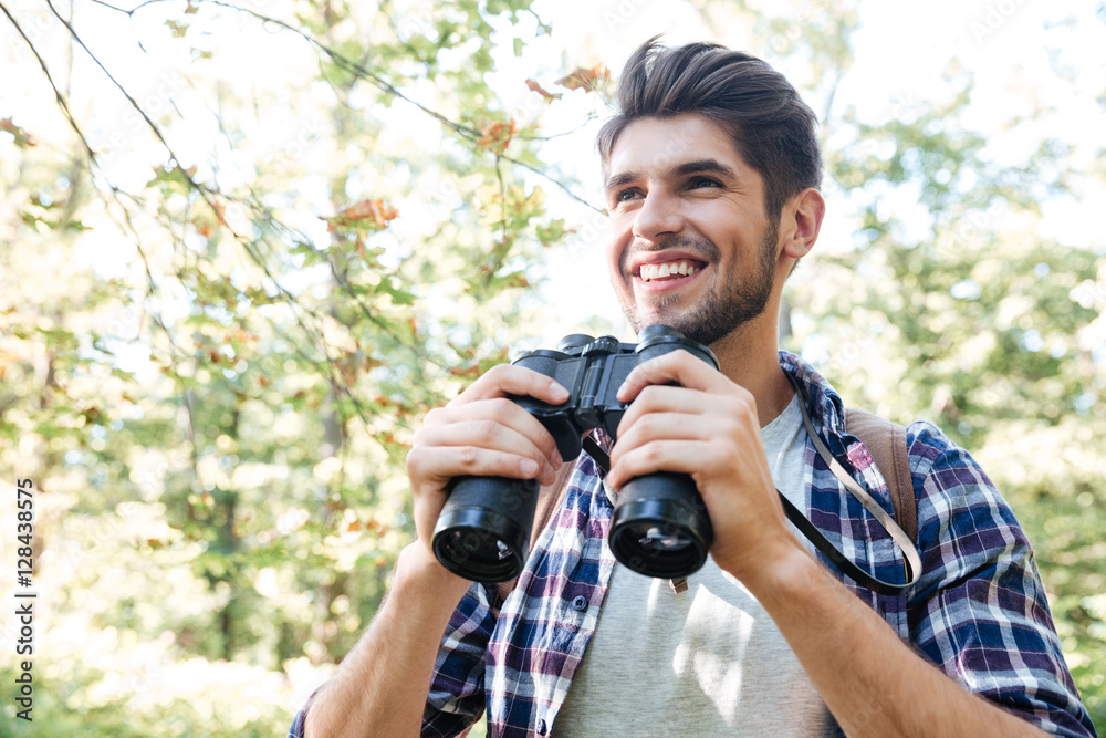 Smiling man with binoculars in forest