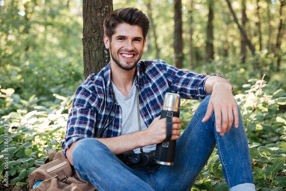 Guy sitting with thermos in forest Guy sitting with thermos in forest