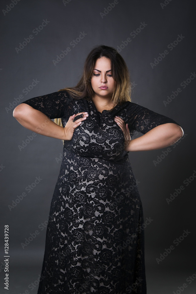 Young beautiful plus size model in black dres, xxl woman on gray