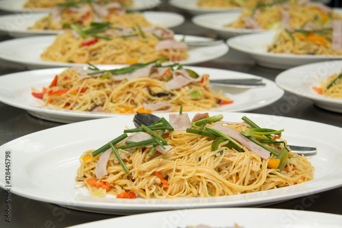 stir fried yellow noodles with ham and vegetable on white dish © mitrs3