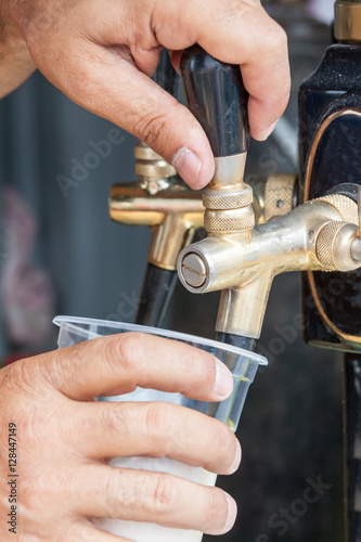 the seller pours beer in a glass from under crane