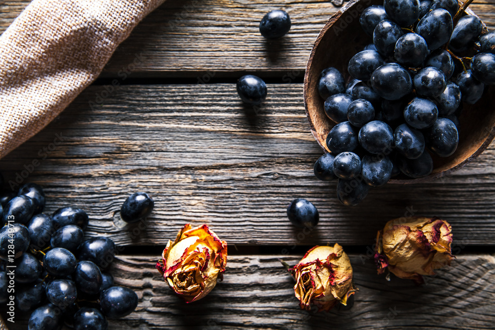 Grapes with dried roses on a wooden background. Fruits, flowers, food Grapes with dried roses on a wooden background. Fruits, flowers, food