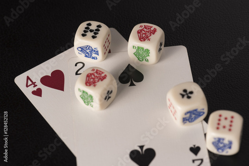 Gaming dice with cards on dark table
