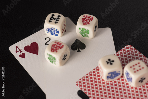 Gaming dice with cards on dark table