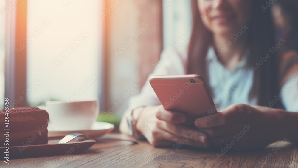 Woman in cafe with smartphone in hands and texting message, sitting alone Woman in cafe with smartphone in hands and texting message, sitting alone