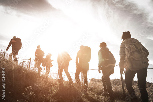 Group of hikers walking on a mountain at sunset photo