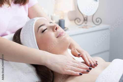 Obraz na płótnie Beautiful young woman receiving facial massage with closed eyes in a spa salon w salonie