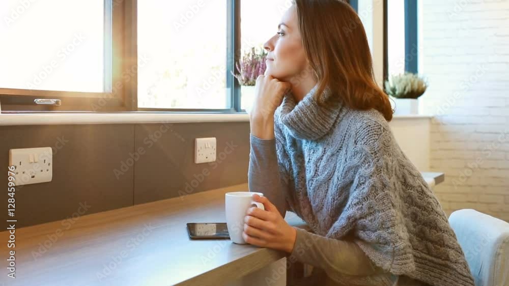 Beautiful young woman enjoying a hot drink in a coffee shop while relaxing and waiting for a friend to arrive