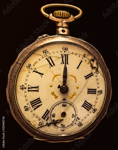 Antique decayed pocket watch isolated on black background, top view