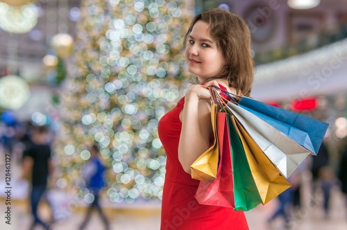 Young woman is shopping gifts for christmas in shopping center.