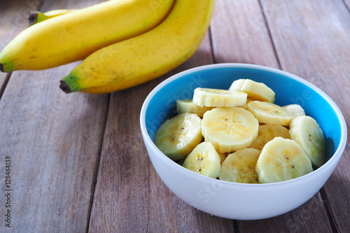Close up of a bowl of sliced ripe banana on wooden background.