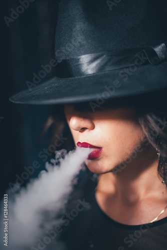 beautiful girl in a black dress smokes hookah on background chains © ShevarevAlex
