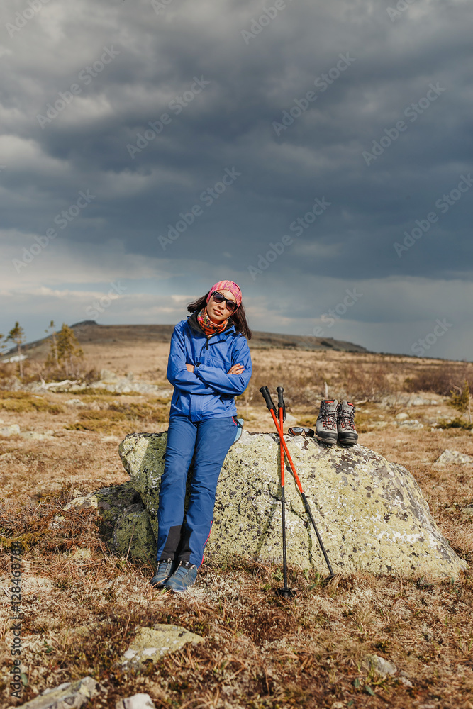Woman hiking in mountains with shoes and trekking poles on mountains
