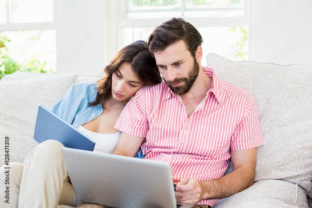 Couple using digital tablet and laptop in living room Couple using digital tablet and laptop in living room